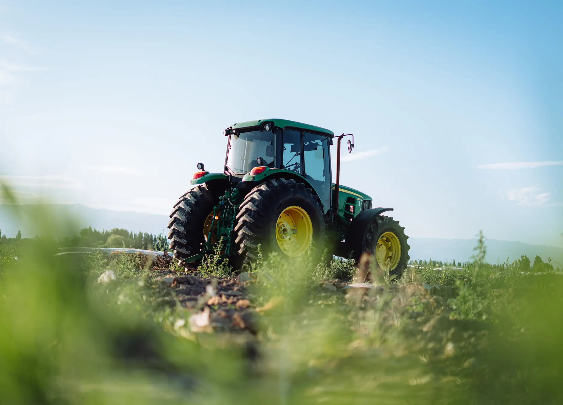 Tracteur vert au travail dans un champ, sous un ciel dégagé