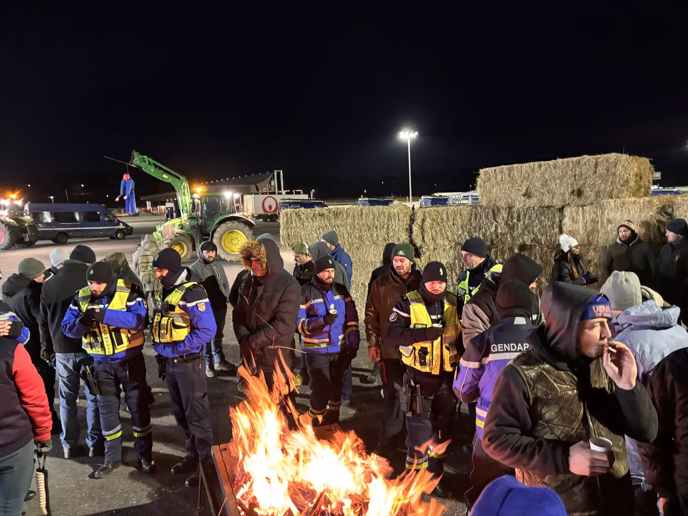 Agriculteurs rassemblés autour d’un feu, près de bottes de paille, au péage de Reventin-Vaugris