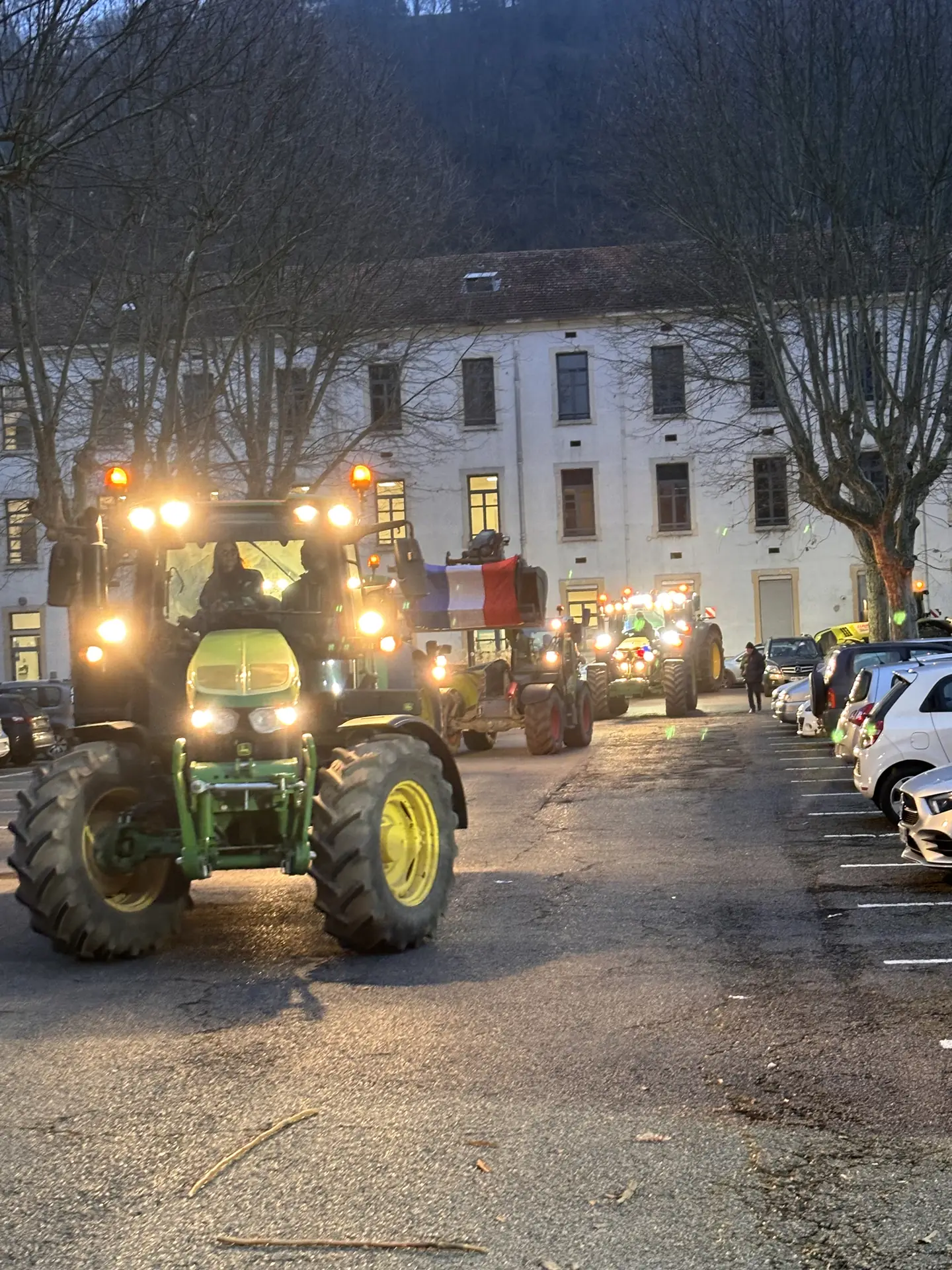 Tracteur aux phares allumés dans une rue de Vienne, de nuit, lors de la mobilisation devant les vœux de Vienne Condrieu Agglo